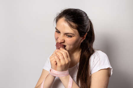 A woman eats smoked sausage, bites violently. Disruption on a diet while losing weight. Refusal of...