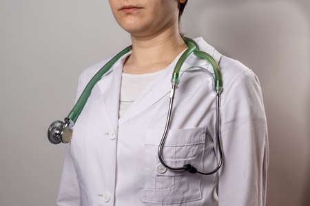 Green stethoscope. A doctor in a white medical uniform and gloves holds a stethophonendoscope.の写真素材