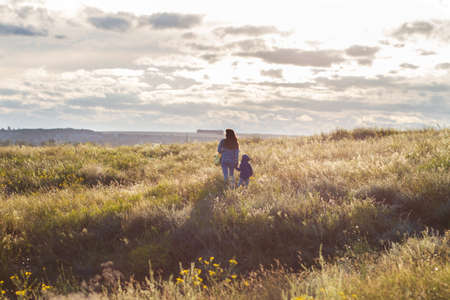Mom and young son walk on the summer field. Happy family, relationshipsの写真素材