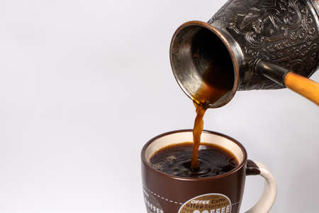 Black coffee in the morning. The process of pouring espresso, americano from copper turk into a...