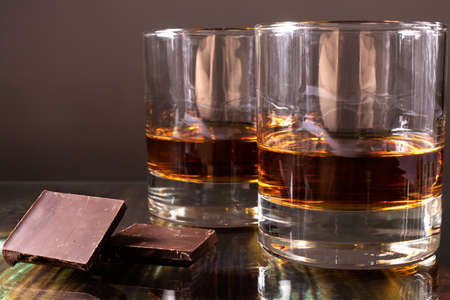 Two glasses with whiskey and pieces of dark chocolate. Appetizer for alcohol, dear spirits.の写真素材