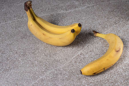 Bananas on a gray stone background. Three ripe yellow bananas.の写真素材