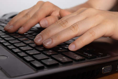 Human hands are typing text on a black laptop keyboard.