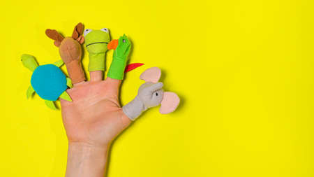 Fingers toys made of fabric on the hand on a yellow background banner with a place for text. Fingers Theaterの写真素材