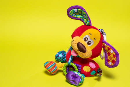 Red orange doggy toy on a yellow background with room for text. Soft toy for baby dog banner for toy store.の写真素材