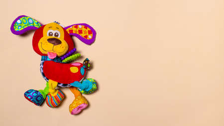 Red orange doggy toy on a beige background with room for text. Soft toy for baby dog banner for toy store.の写真素材