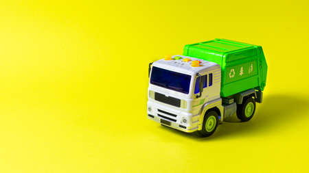 The toy is a garbage truck green with a white body on a yellow background banner with a place for text for a toy store. Children's toys typewriterの写真素材