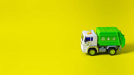 The toy is a garbage truck green with a white body on a yellow background banner with a place for text for a toy store. Children's toys typewriterの写真素材