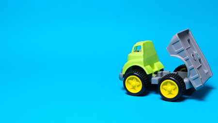 Toy truck car on a blue background - construction equipment for children. Bright childrens plastic toys, dump truck childhood. Copyspace banner place for text.の写真素材