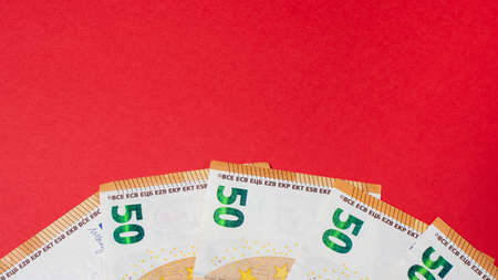 Fragment of the 50 fifty euro banknote on a red background. Close up currency money with place for...