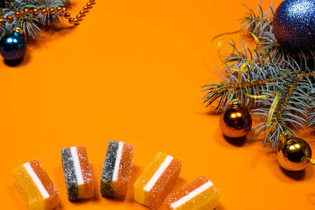 Marmalade and spruce twig with a ribbon and a toy on a red background. A banner on a red background with a place for copyspace textの写真素材