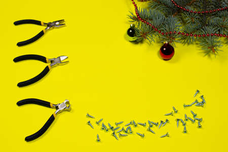 Construction tools pliers, rounds and self-cutters with a Christmas tree with a place to text on a yellow background. New Year's banner for a construction storeの写真素材