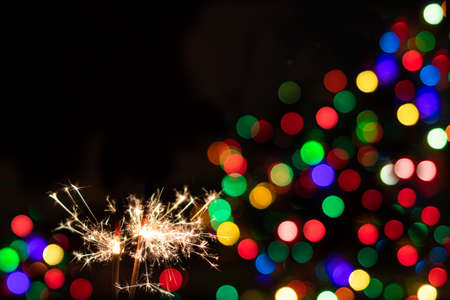 Sparkler on festive bokeh background. Festive greeting card for new year and christmas 2021, colorful lights in the backgroundの写真素材