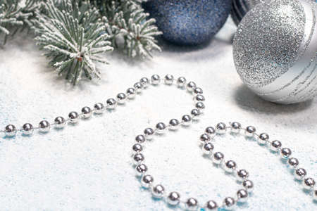 Spruce branch with Christmas toys and beads on a snow-covered white background. A holiday card, postcard.の写真素材