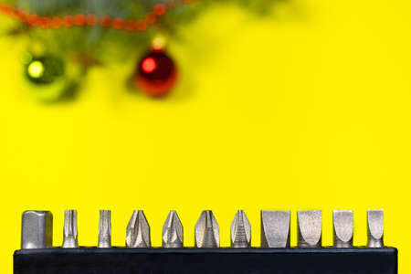 A set of nozzles for a screwdriver on a yellow background with New Year's decoration 2021. With a place for copyspace textの写真素材