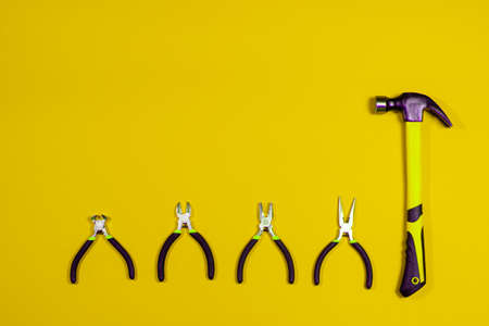 Clippers, pliers, tongs, rounds and hammer on a yellow background. Construction tools with a place for copyspace text. Repairing, building materials store.の写真素材