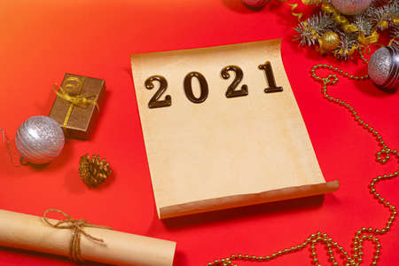 Parchment paper and a scroll for the to-do list and text for the new year 2021 on a red background. Christmas, holiday card with plans for next yearの写真素材