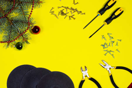 Cutting wheel for metal, screws and a screwdriver on a yellow background with a spruce branch. New year banner for hardware store and construction.の写真素材
