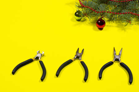 Construction tools pliers, rounds with a Christmas tree with a place to text on a yellow background. New Years banner for a construction store.の写真素材