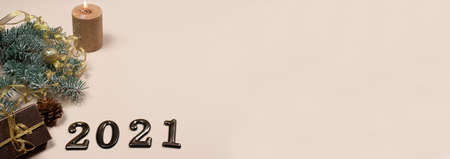 New Years card with figures 2021, gift and spruce branch on a beige background banner with a place...