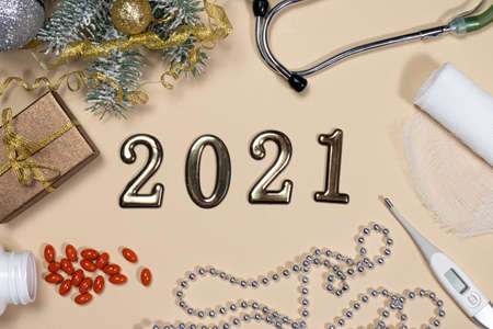 New Year's card on medical subjects: figures 2021, phonendoscope, tablets, thermometer and bandage...