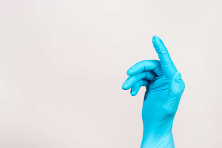 The hand of a proctologist in a glove on a white background. Rectal finger examination for hemorrhoids and diseases of the anus and rectum. Banner with a place for textの写真素材