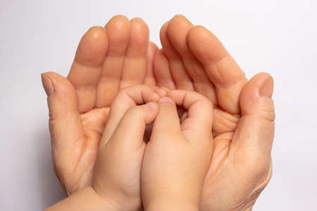 Small children's hands in the hands of an old grandmother. Old age and childhood, communication of grandmother with grandson, aging, age and lifeの写真素材
