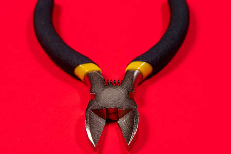 Nippers on a red background tool for cutting wires, cables and wire, for the electrician. The needle...