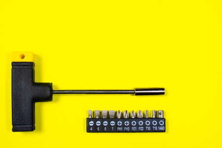 A set of screwdriver nozzles and a screwdriver on a yellow background with space for copyspace text. Tools for construction and repair shop.の写真素材