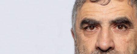 A man with cataracts is a disease of the lens of the human eye, clouding. Comparison of healthy and sick eye banner with place for text on a gray backgroundの写真素材