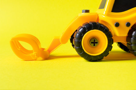Tractor nozzle in the form of forceps - log loader, construction toy typewriter on a yellow background.の写真素材