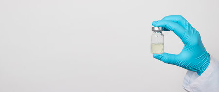 A doctor or laboratory technician holds a test tube with a vaccine against diseases. Vaccination against covid-19 coronavirus, influenza, tuberculosis, diphtheria, tetanus and rabies. Pandemic in the world, the invention of the vaccine.の写真素材