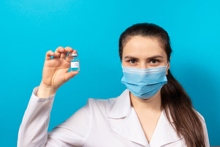 A doctor or lab technician holds a polio vaccine on a blue background. Vaccination and prevention poliomyelitis. Infantile paralysisの写真素材