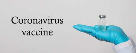 A doctor or laboratory technician holds a test tube with a vaccine against diseases. Vaccination against covid-19 coronavirus. Pandemic in the world, the invention of the vaccine. Banner text placeの写真素材