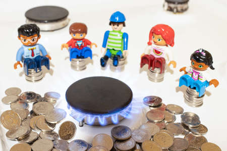 People sit near the gas burner on the stove and coins of money. The price of gas and utilities in...