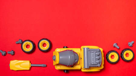 A set of parts and tools to collect the designer of the truck mixer machine on a red with copyspace...
