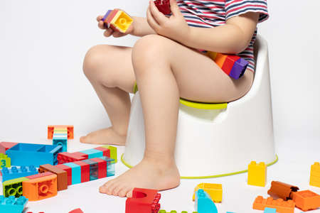 A little boy sits on a pot and plays with multi-colored designer cubes. Get used to the potの写真素材