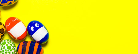 Multicolored Easter eggs on a yellow background. Eggs with faces put on protective masks against during quarantine, yellow banner.の写真素材
