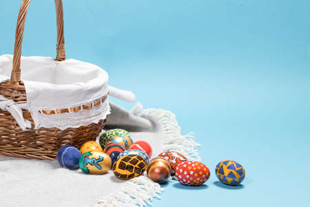 Delicate minimalist Easter photo - a wicker basket and painted eggs on a blue background copy space for textの写真素材