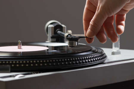 A man and vintage record player while recording, the record spins and music plays. Gramophone and antiquity ideaの写真素材