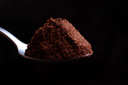 A breathtaking photo of ground coffee in a spoon on a black background. Aromatic morning coffee smell, aromatherapy.の写真素材