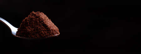 A breathtaking photo of ground coffee in a spoon on a black background. Banner with place for text for advertising or offer of a coffee shop.の写真素材