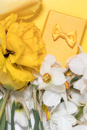Yellow vertical photo with daffodils, tulips and gift box. For congratulations on holidays, happy...