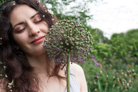 Beautiful woman near plants in the summer garden. With space for text to advertise dietary supplements, natural cosmetics or herbal medicineの写真素材