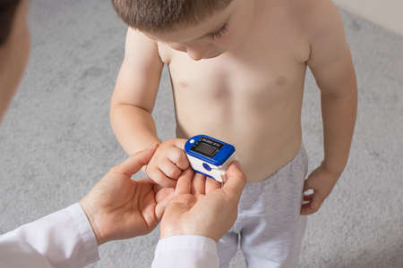 The pediatrician measures the childs blood oxygen level with a pulse oximeter. Pneumonia and in childrenの写真素材