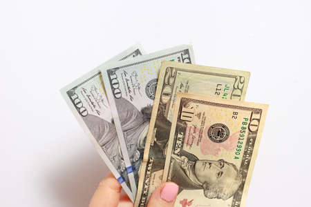 A womans hand holds many dollar bills on a white. Credit, corruption, borrowing money and financial...