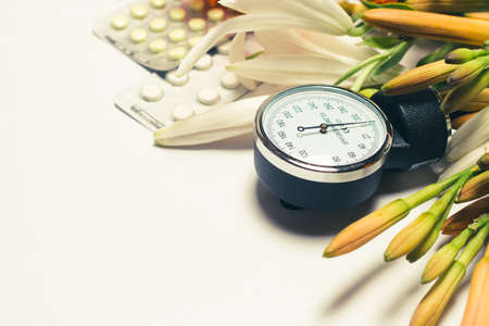 Sphygmomanometer for measuring blood pressure and pills. Hypertension day, photo for cardiology and heart disease with place for text on white.の写真素材
