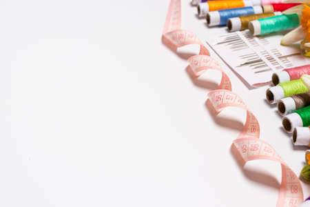 Tape measure, threads and needles on white with space for the text of the banner. For the worker...