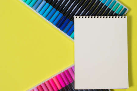 Colored felt-tip pens and a notebook on a yellow background with a place for text top view. Bright banner for a stationery store.の写真素材