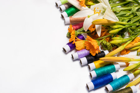 Multicolored threads and flowers on a white background with copy space for text. Greeting card for a...